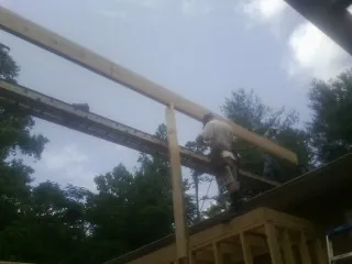 Carpenter setting a ridge beam over a new addition frame — Ice Dam Removal by Roofing Brothers in Olivia