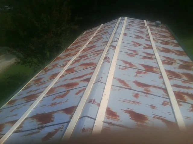 Rusted metal roof panels with new wood purlins before replacement — Storm Damage Roof Repair in Olivia by Roofing Brothers