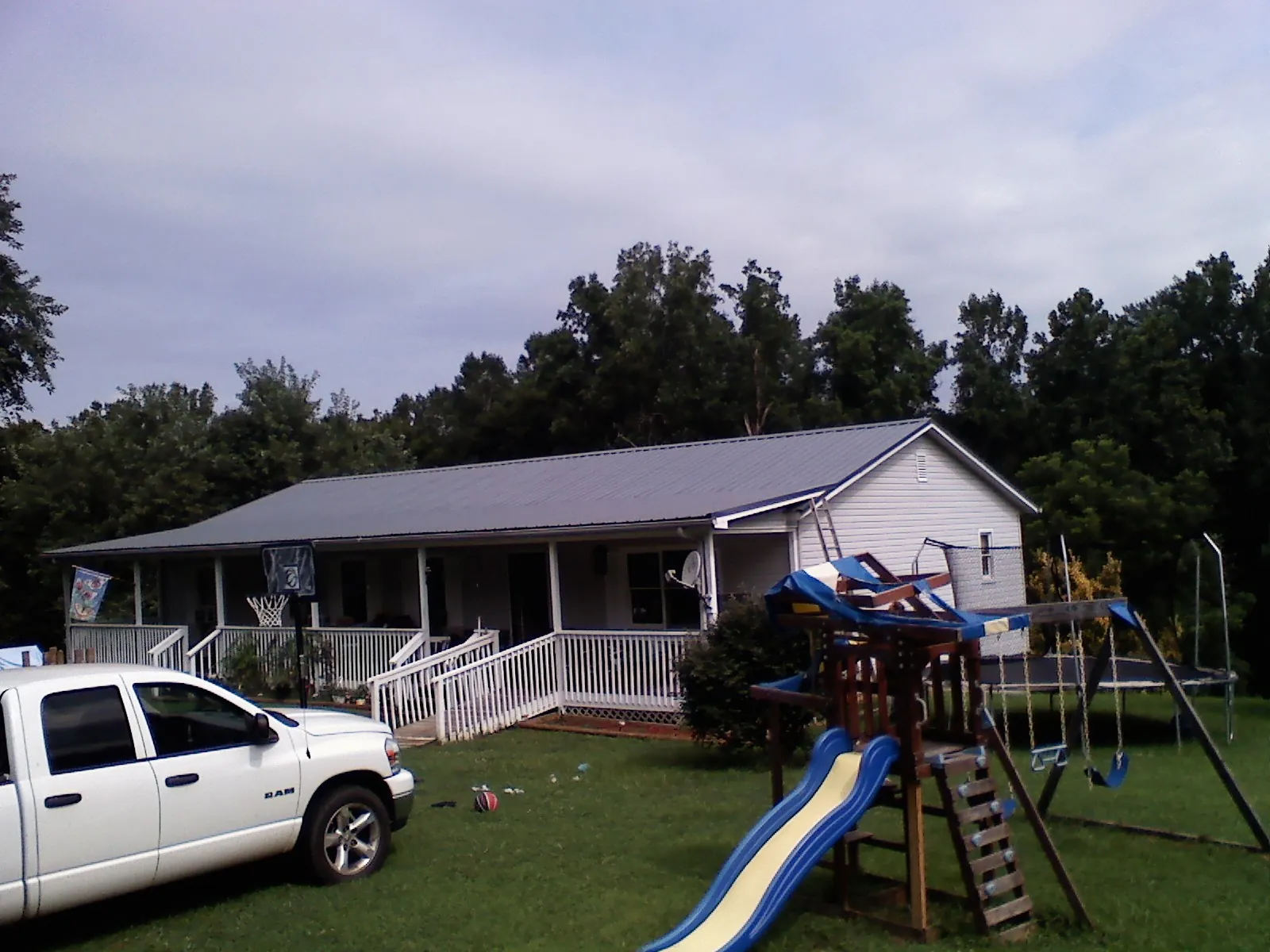 Dark metal roof on a country home with a full length front porch in Olivia