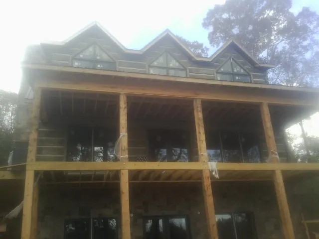 Dormers and porch framing on a large log home under construction — Roof Coating work by our crew in Olivia